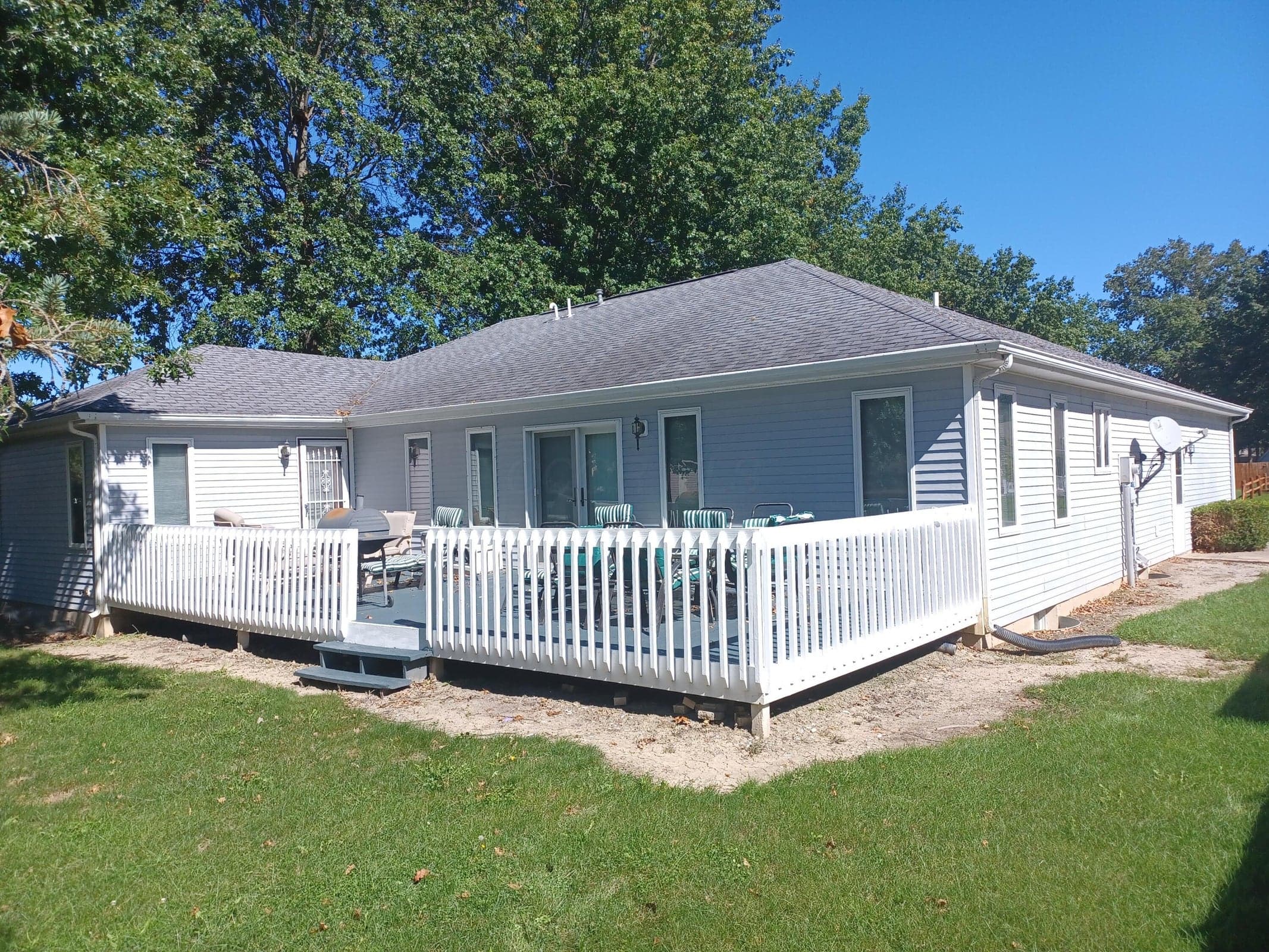 Elevated exterior deck featuring white picket-style railing, stairs, horizontal siding, and glass sliding door access.
