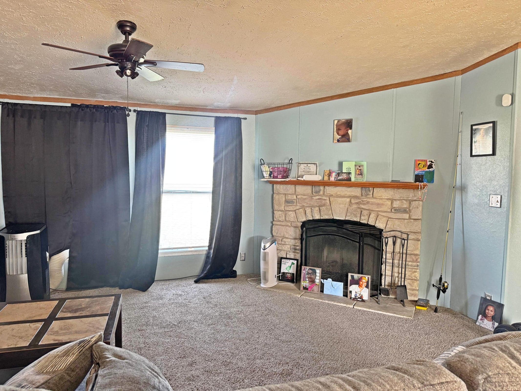 Fireplace featuring a stone-style facade and wooden mantel, paired with a ceiling-mounted fan and wall-to-wall carpeting