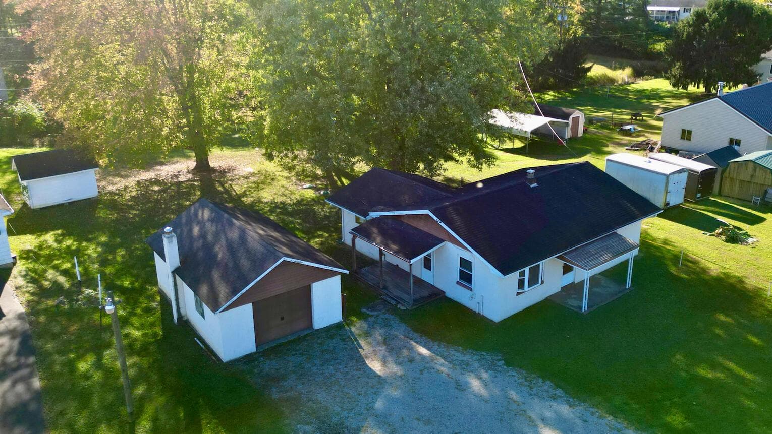 Detached garage, covered porches, mature trees, and expansive grassy grounds