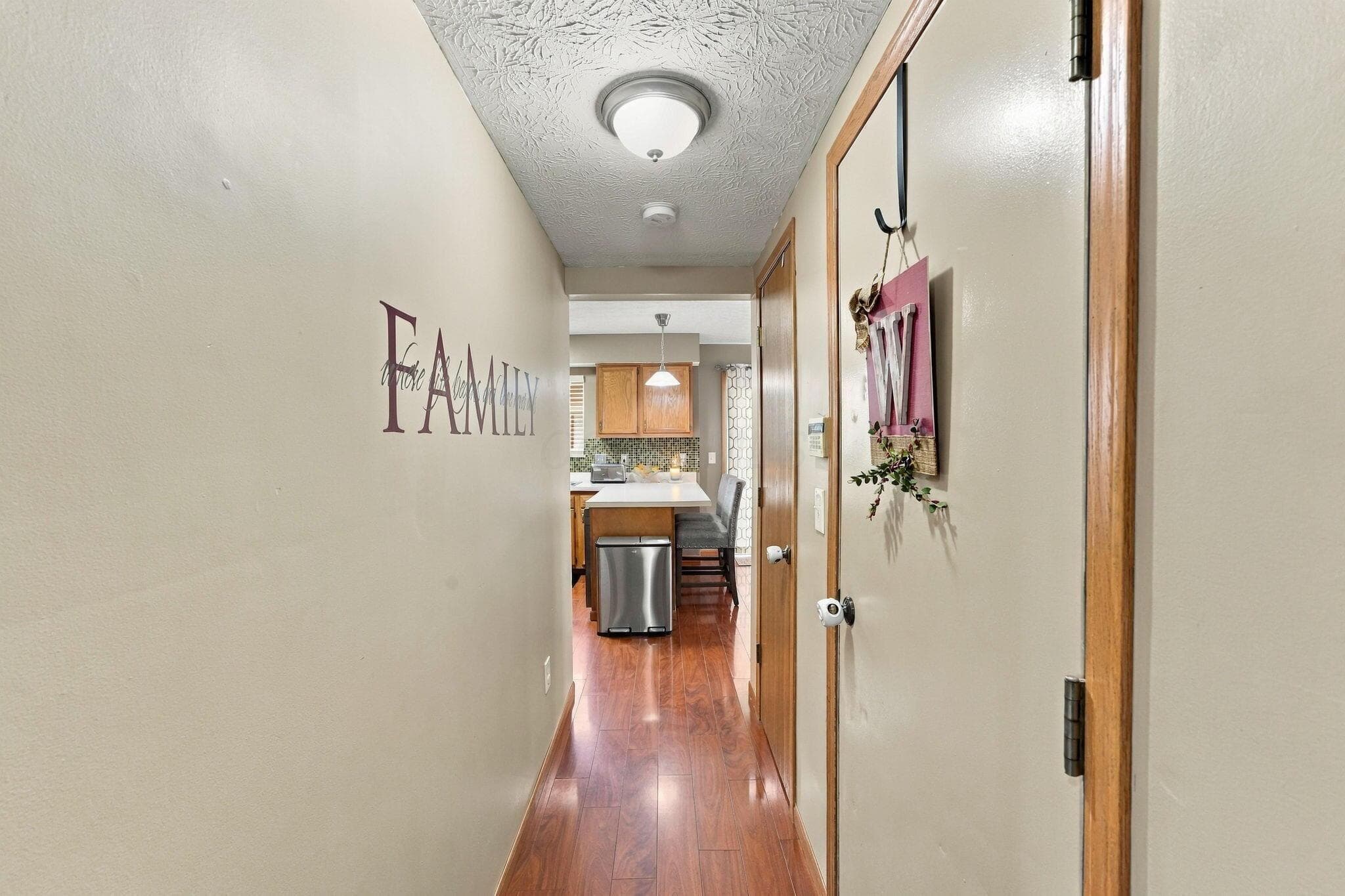 Hallway featuring wood-finish flooring, textured ceiling, and flush-mount light fixture