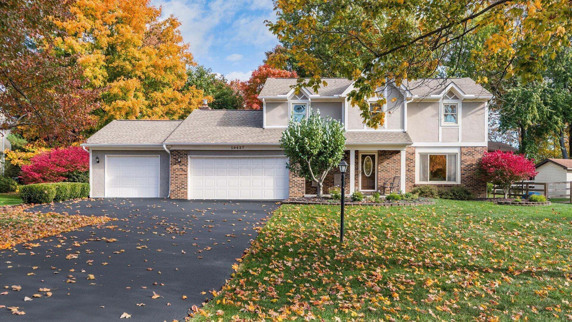 Exterior featuring a brick and siding facade, an attached three-car garage, and a paved driveway