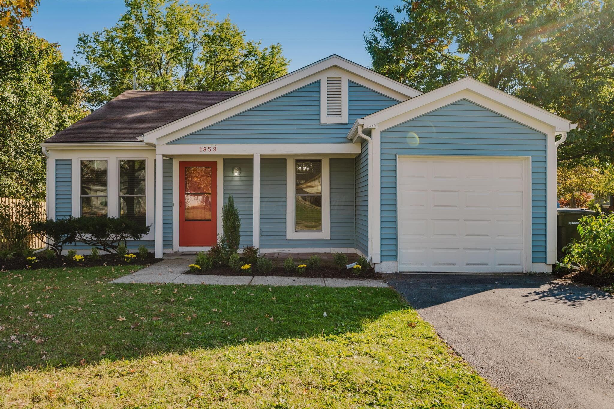 Blue siding exterior featuring a gable roof, covered front porch, attached one-car garage, and asphalt driveway
